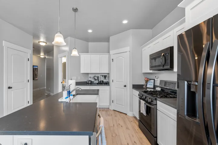 Contemporary kitchen featuring white cabinetry, dark countertops, and wood-finish flooring