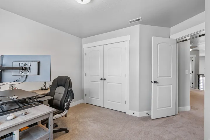 Carpeted room featuring a white two-panel arched door, white bi-fold closet doors, and white baseboards
