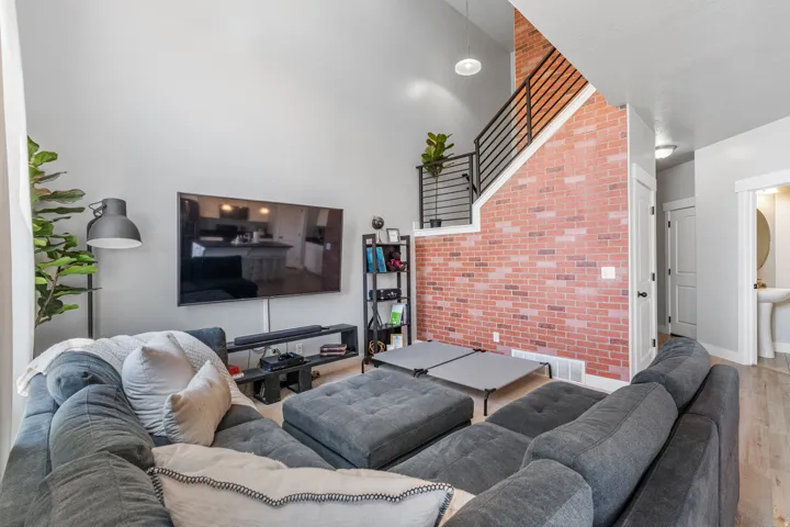 Vaulted ceilings highlight the accent brick wall and open staircase with metal railings