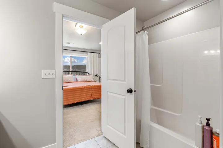 Bathroom featuring a white shower-over-tub combination with an integrated soap dish and a white shower curtain rod
