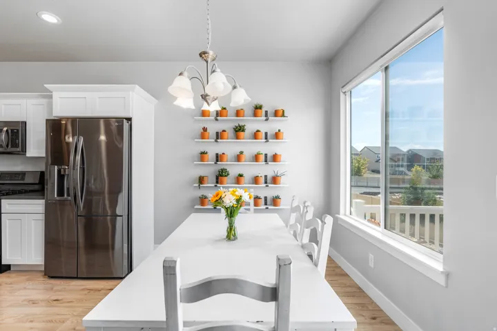 Bright dining area featuring a modern chandelier, extensive wall shelving, and a large picture window