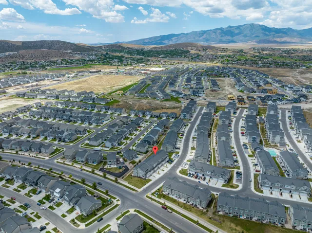 Expansive residential community featuring a mix of single-family homes and townhomes, a structured street grid, and mountain backdrops