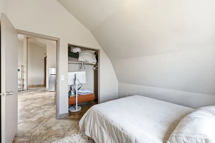 Bedroom featuring an angled ceiling, an open closet with built-in shelving, and light-toned wall paint