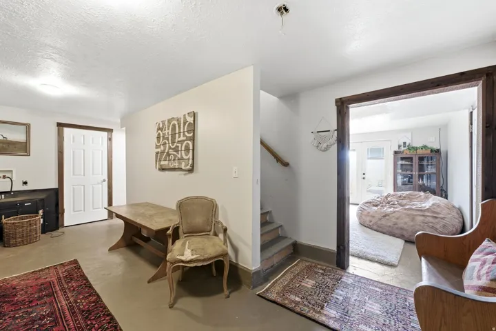 Finished lower level space featuring a white paneled door, wood trim accents, and a staircase with a wood handrail
