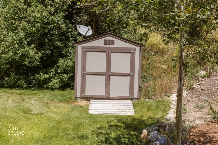 Freestanding storage shed with dual doors and a wooden ramp