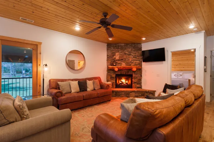 Living area featuring a corner stone fireplace with a wood mantel