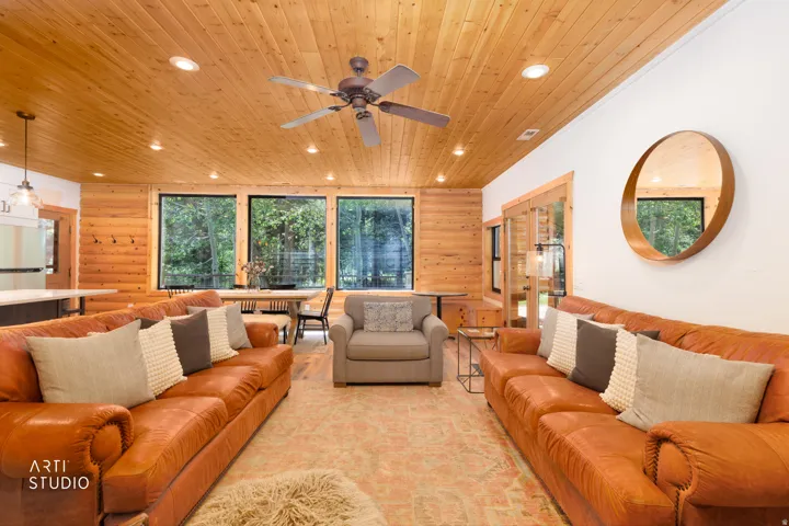 Living area featuring a prominent corner stone fireplace with a wood-finish mantel, wood-plank ceiling, recessed lighting, and a ceiling fan