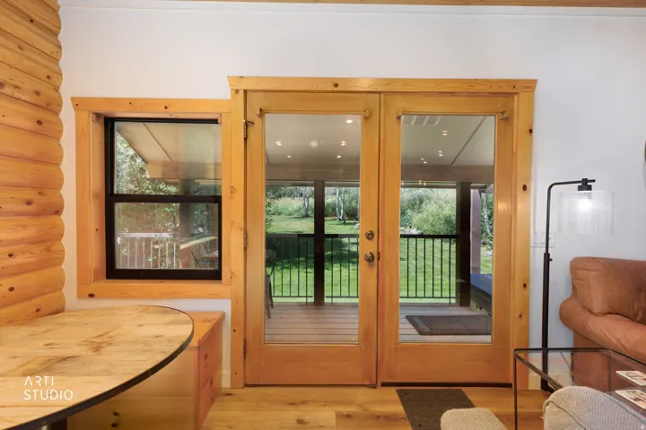 French doors with natural wood trim open to an outdoor covered deck,  feauturing a covered hot tub, and views that will take your breath away.