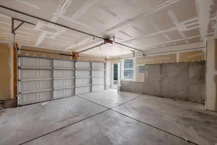 Concrete flooring with expansion joints, two garage doors, and a window for natural light
