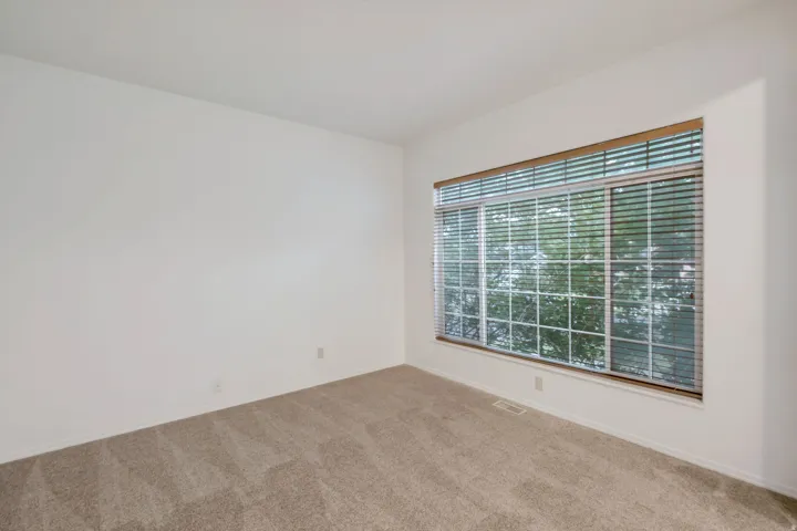 Expansive window with horizontal blinds and wood-finish valance, offering natural light