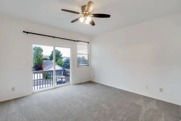 Carpeted room featuring a ceiling fan with integrated lighting, a sliding glass door providing outdoor access, and a window with horizontal blinds