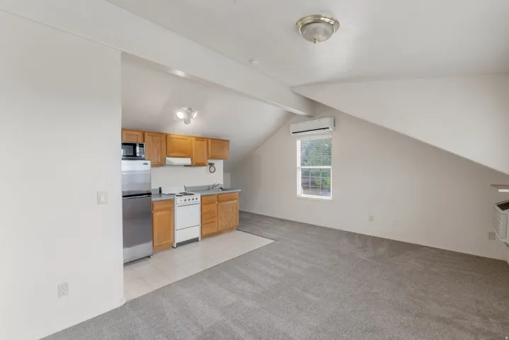 Compact kitchen featuring wood-finish cabinetry, stainless steel refrigerator, and built-in microwave