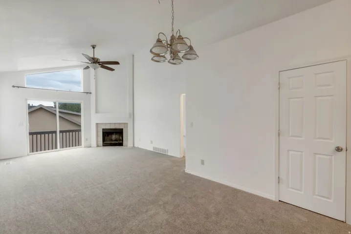 Spacious living area featuring a vaulted ceiling and light gray carpet flooring