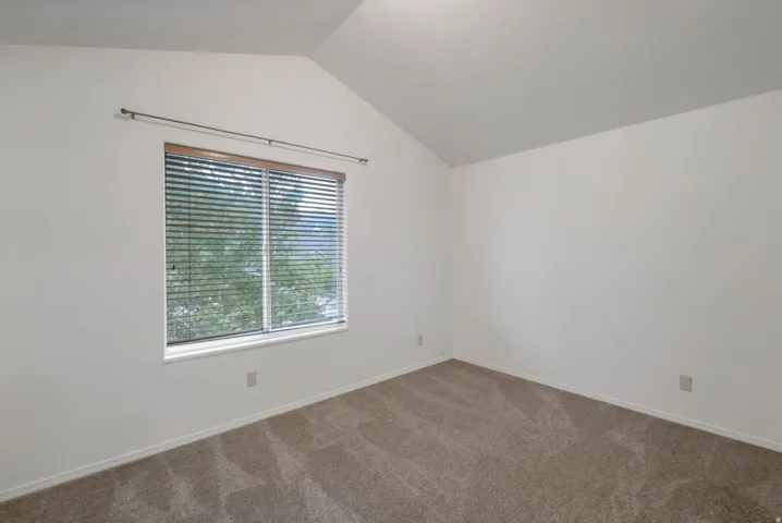 Room featuring a vaulted ceiling and neutral-toned carpeting