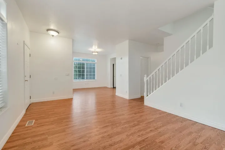 Spacious interior featuring wood-finish flooring, white walls, and a prominent staircase with white balusters