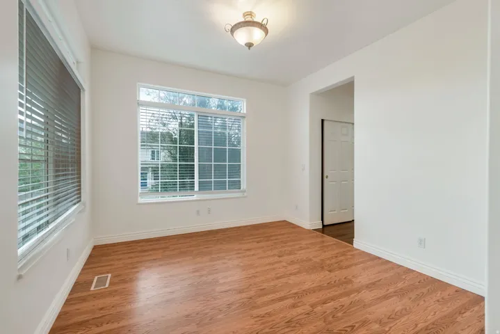 Spacious room featuring wood-finish flooring, white baseboards, and bright white walls