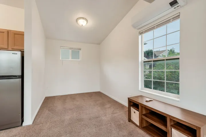 Vaulted ceiling room featuring a large grid-pattern window, recessed lighting, and a wall-mounted air conditioning unit