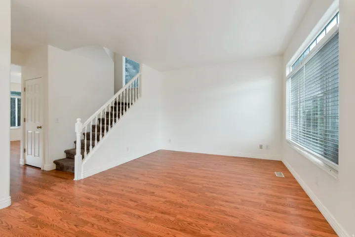 Bright main living area featuring wood-finish flooring, white walls, and white baseboards