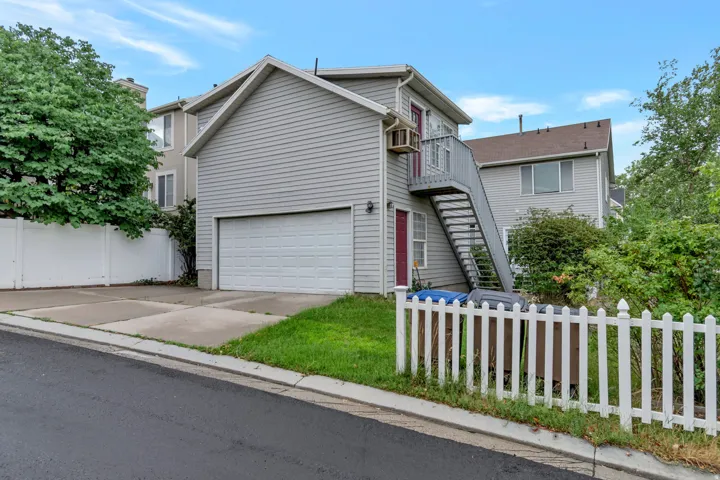 Two-story residence featuring light gray siding and an attached garage with a white sectional door