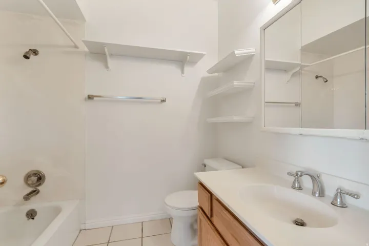 Bathroom featuring a light-toned vanity with an integrated sink, a mirrored medicine cabinet, and a bathtub with shower fixture