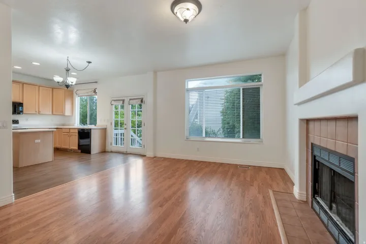 Open-concept living space featuring wood-finish flooring, a tiled fireplace with mantel, and a large picture window