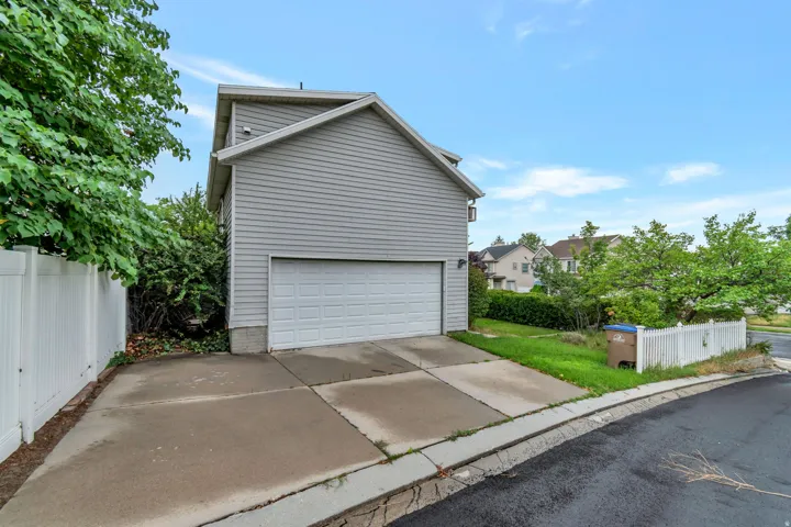 Attached two-story residence featuring light gray horizontal siding and a white paneled garage door
