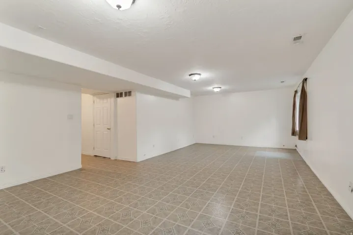 Spacious room featuring patterned floor tiles, white walls, and a white ceiling