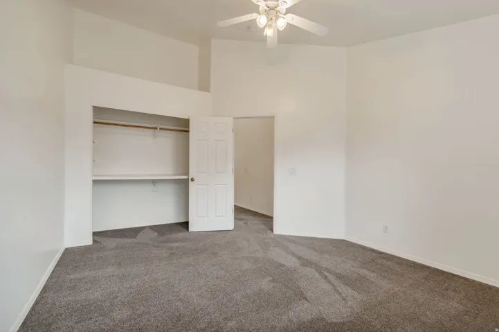 Spacious interior room with neutral-toned walls, vaulted ceiling, and grey carpet