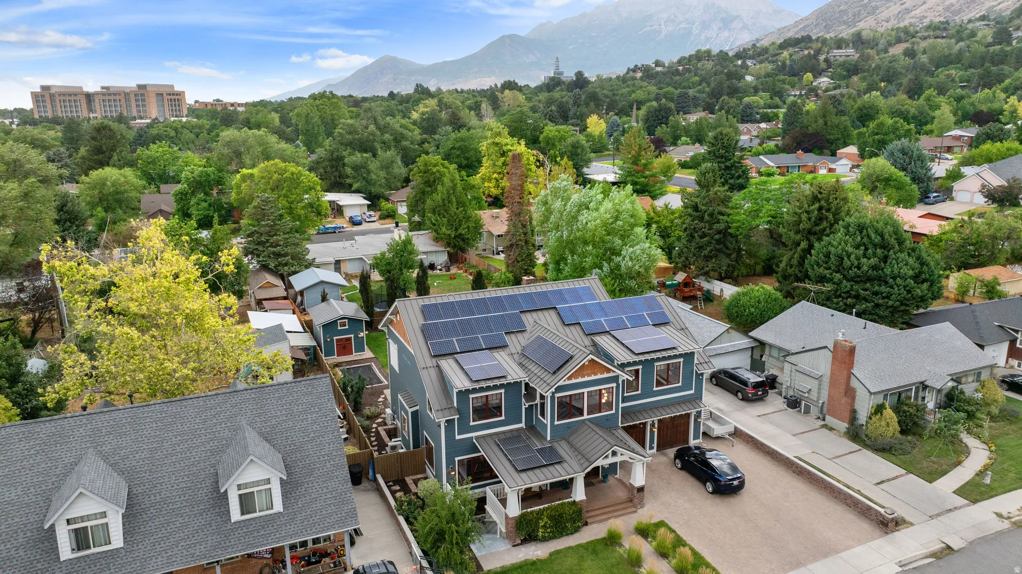 Contemporary multi-story residence featuring a blue exterior with contrasting trim, multiple rooflines, and integrated solar panels