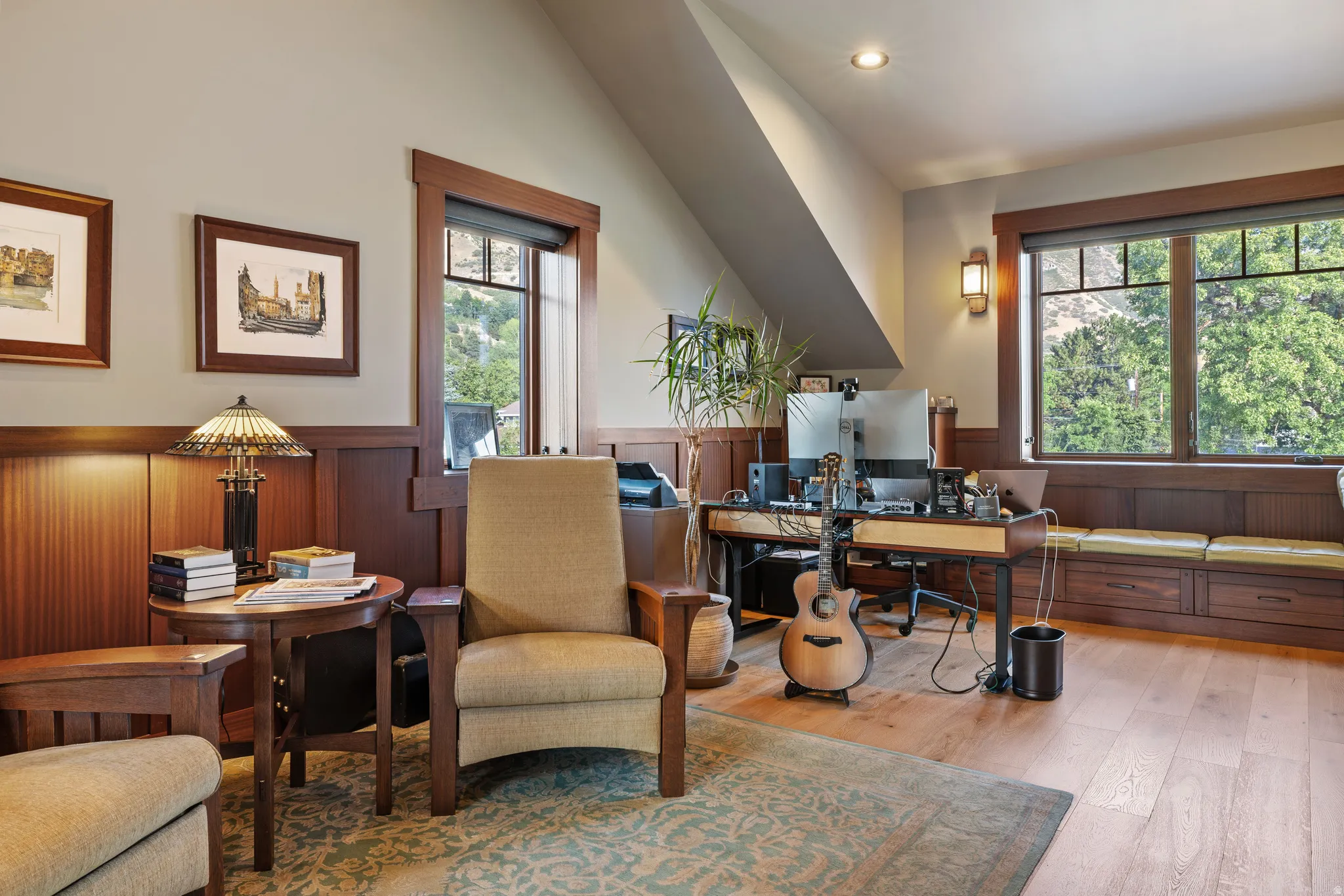 Spacious room featuring wood-finish flooring, accent wall paneling, built-in window seating with storage, and a large window with natural light