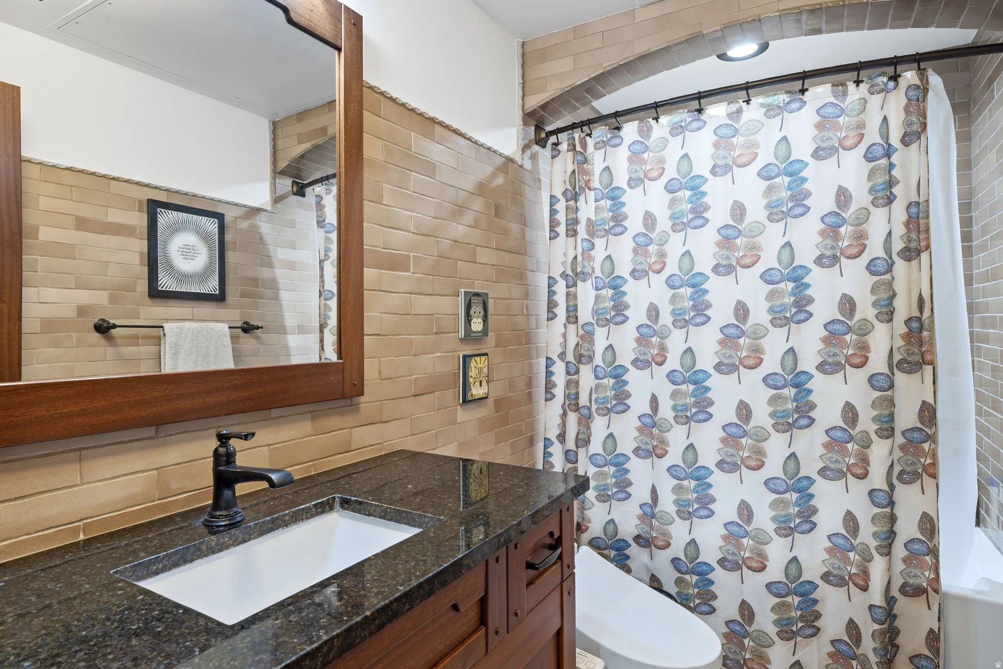 Bathroom featuring a dark wood vanity with a stone countertop, an undermount sink, and a dark bronze faucet