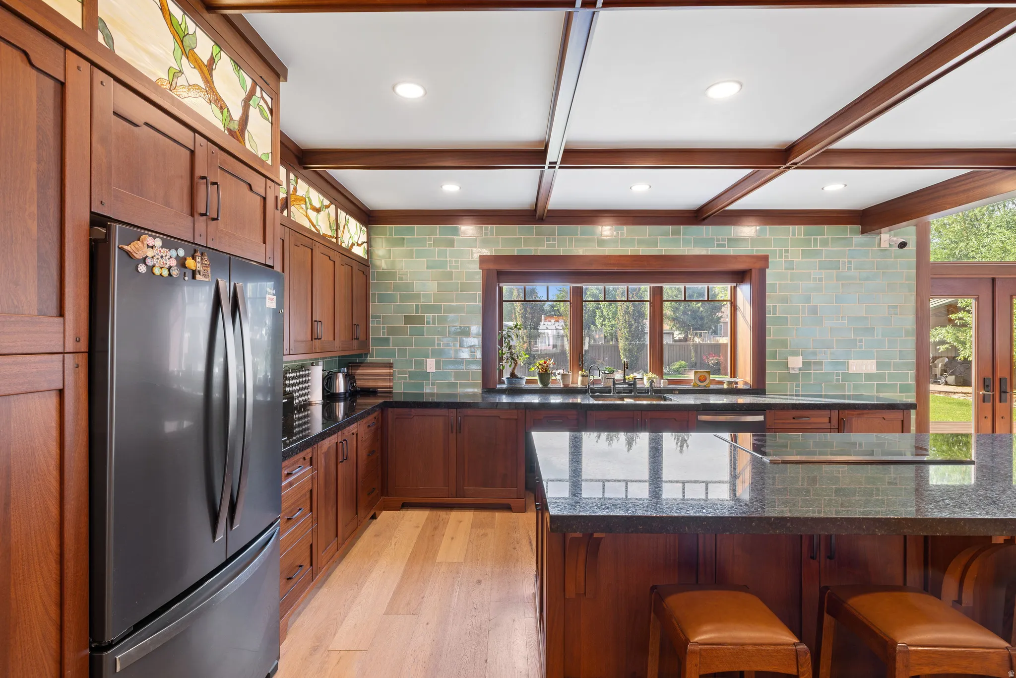 Kitchen featuring wood-finish cabinetry, light wood-finish flooring, and a large central island with a dark stone countertop