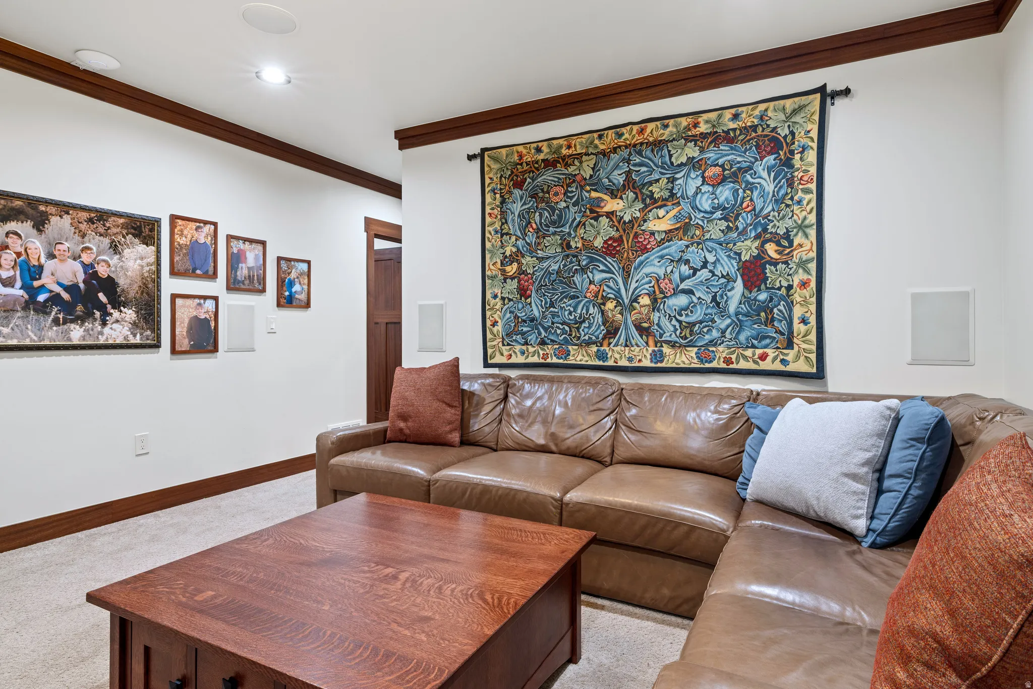 Basement warm living space featuring recessed ceiling lighting, wall-mounted speakers, and wood trim accents