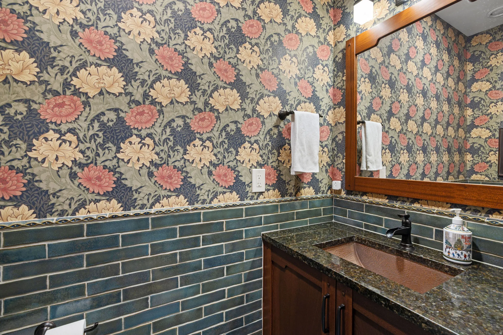 Vanity featuring a dark granite countertop, integrated copper-tone sink, and dark wood-finish cabinetry