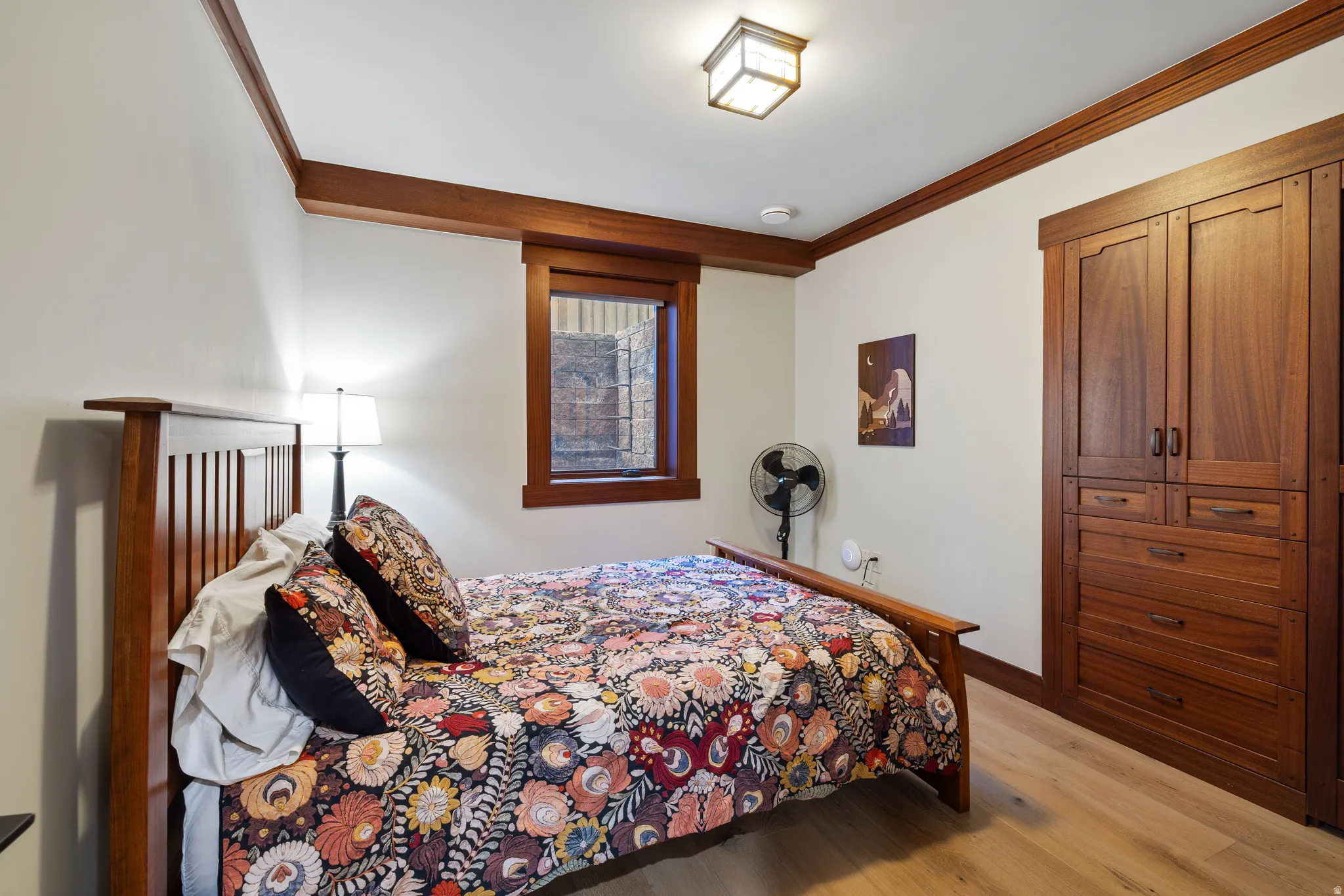Bedroom featuring built-in wood cabinetry, wood-finish flooring, and a wood-trimmed window