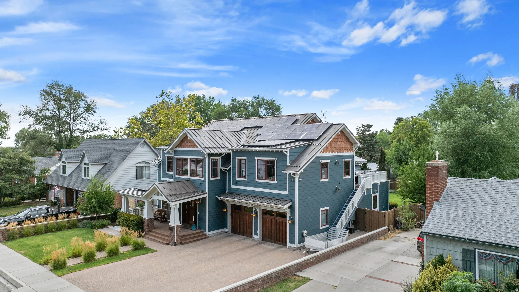 Multi-story residence featuring blue siding, a metal roof, and solar panels