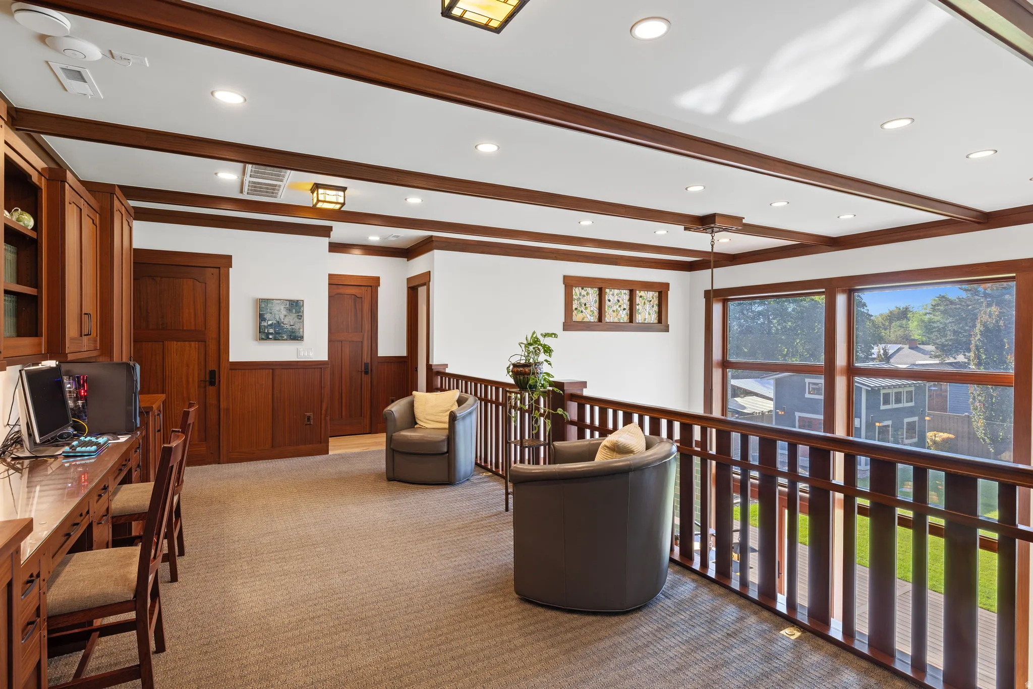 Spacious loft with light-colored carpeting, recessed lighting, and extensive wood-paneled walls and trim
