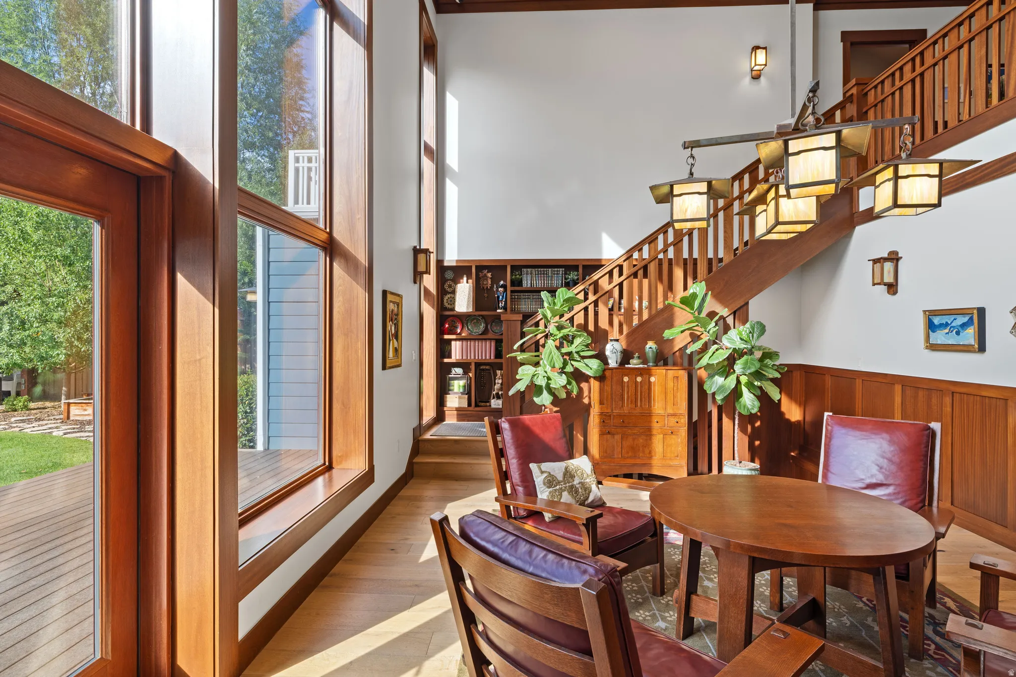 Two-story foyer featuring tall windows with natural wood frames, a grand staircase with wood railings, extensive wainscoting, and wood-finish flooring