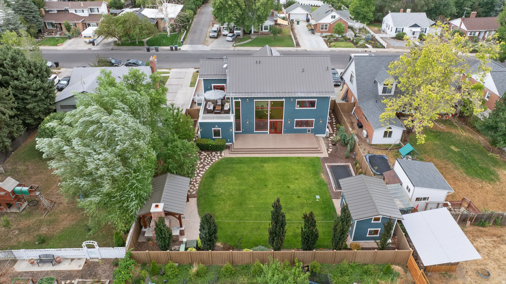 Blue exterior residence with a metal roof, featuring a spacious wood-finish deck