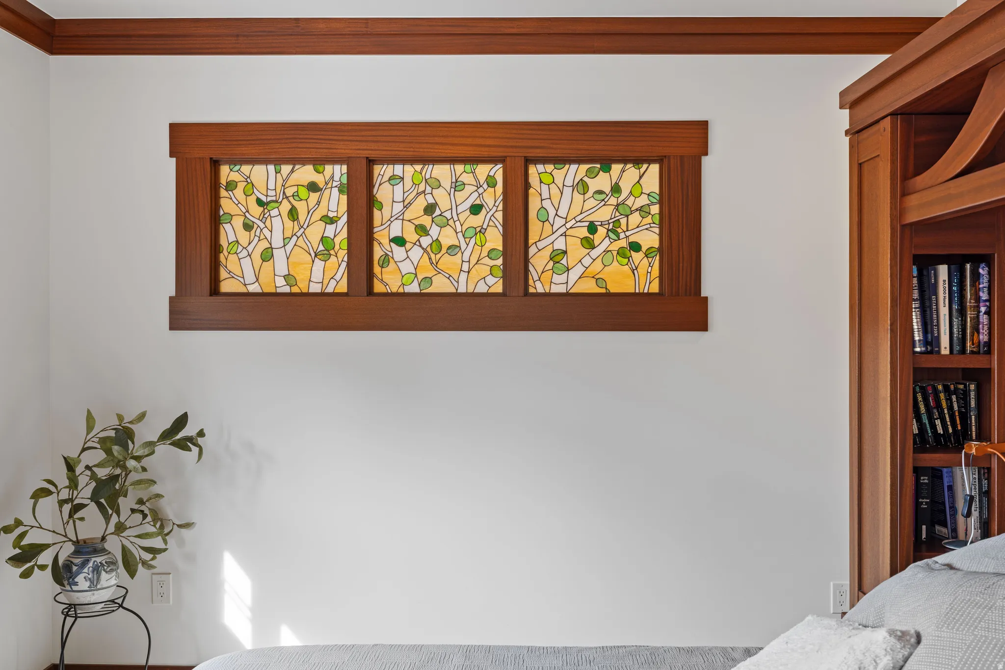Three-panel stained glass window featuring a tree motif, framed by wood trim