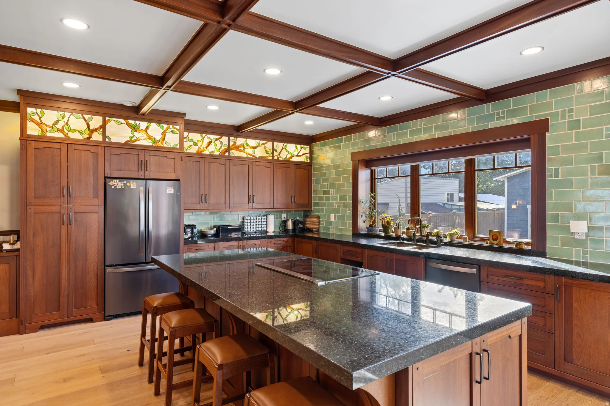 Kitchen featuring a large central island with integrated cooktop, extensive wood cabinetry, and a full-height tile backsplash