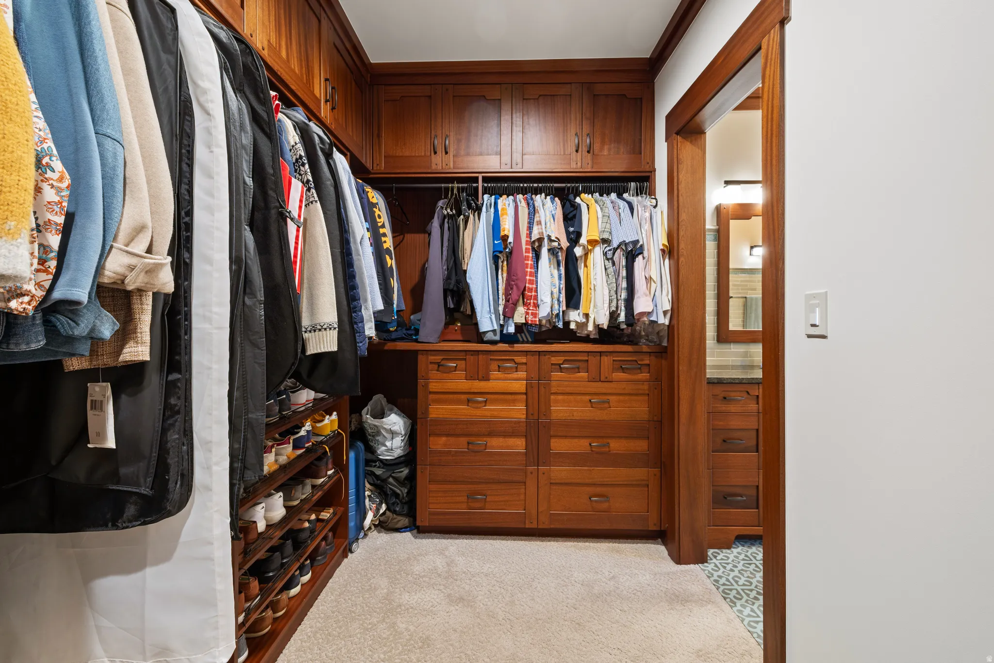 Custom closet with warm wood-finish cabinetry and trim, built-in drawers, and extensive hanging rods