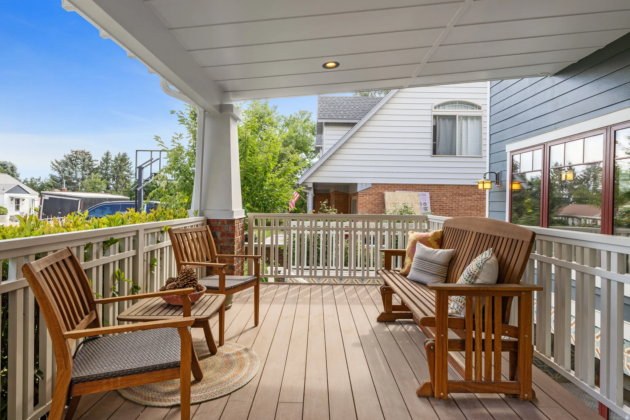 Covered front porch featuring durable composite decking, white railings, and a recessed ceiling light