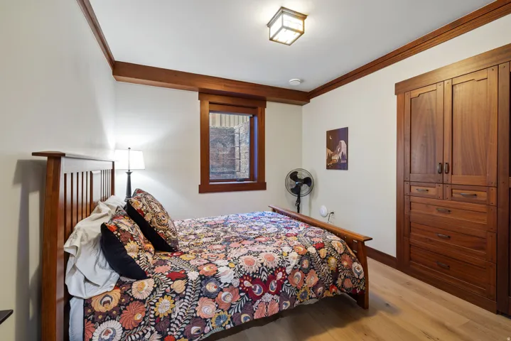 Bedroom featuring built-in wood cabinetry, wood-finish flooring, and a wood-trimmed window