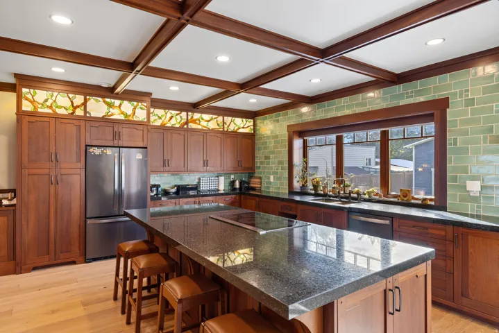 Kitchen featuring a large central island with integrated cooktop, extensive wood cabinetry, and a full-height tile backsplash