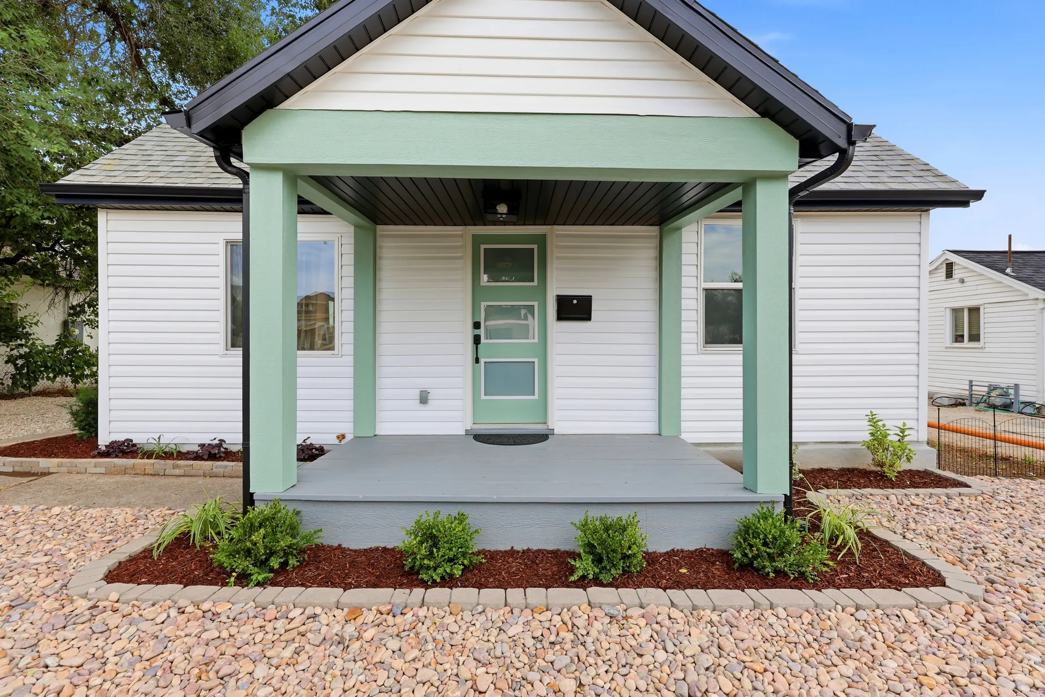 White horizontal siding exterior with a covered porch featuring light green columns and trim