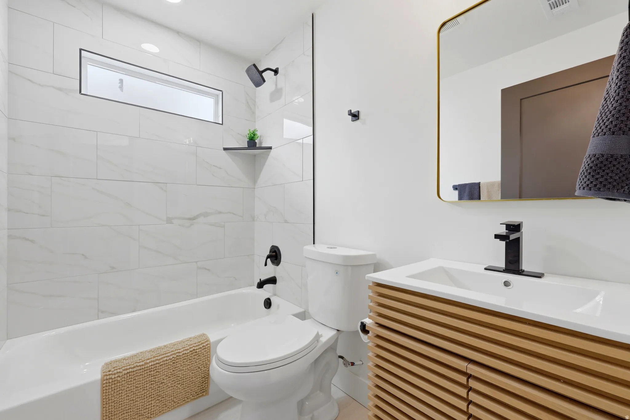 Bathroom featuring a built-in tub with matte black fixtures, white subway tile surround, and a horizontal transom window