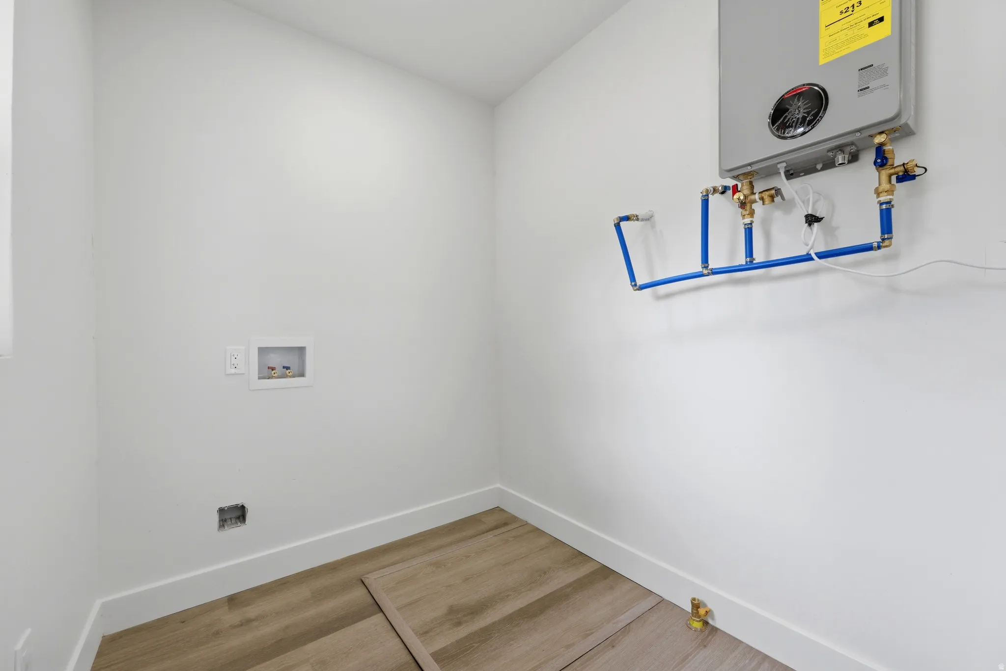 Utility area featuring a wall-mounted tankless water heater, PEX plumbing, and a washing machine hookup