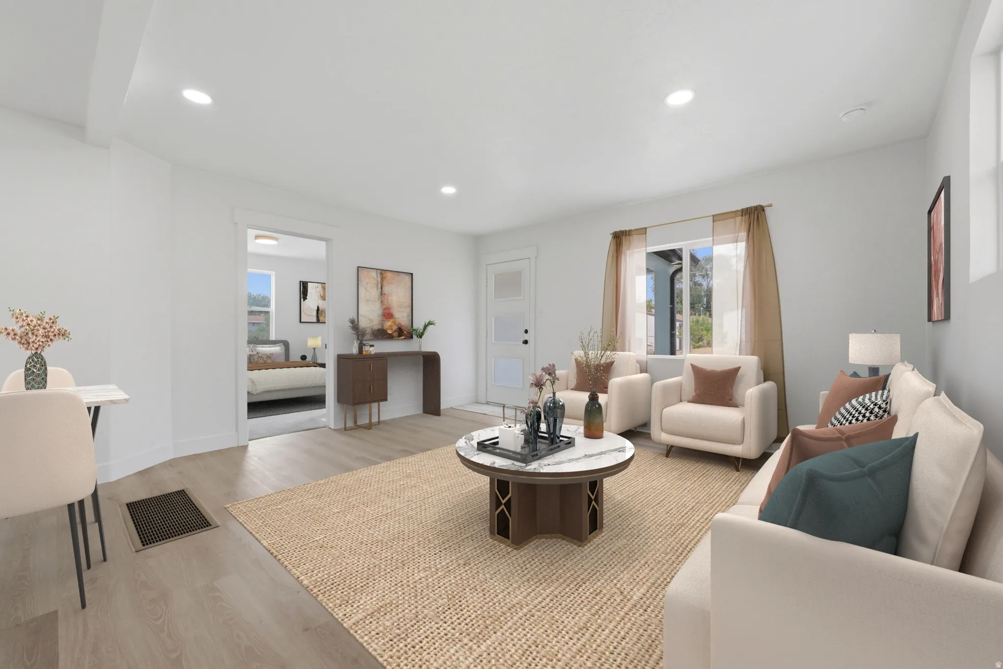 Spacious living area featuring light wood-finish flooring, recessed lighting, and bright white walls