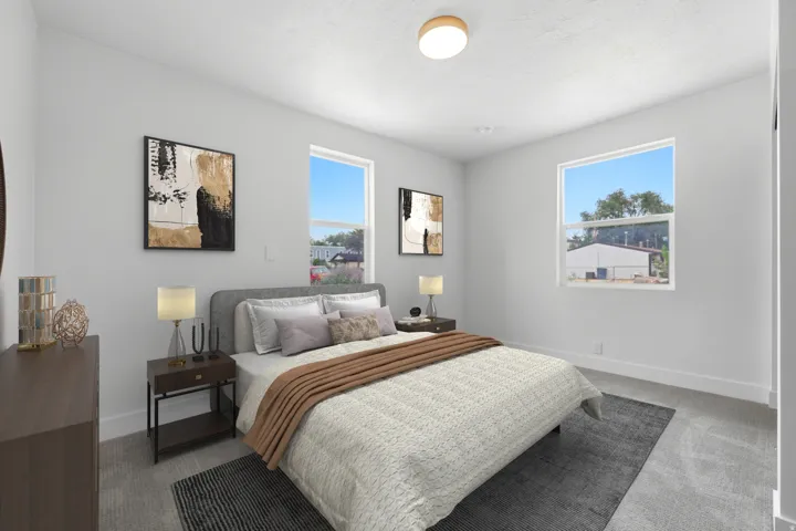 Spacious bedroom featuring light-colored walls, carpeted flooring, and two large windows providing ample natural light
